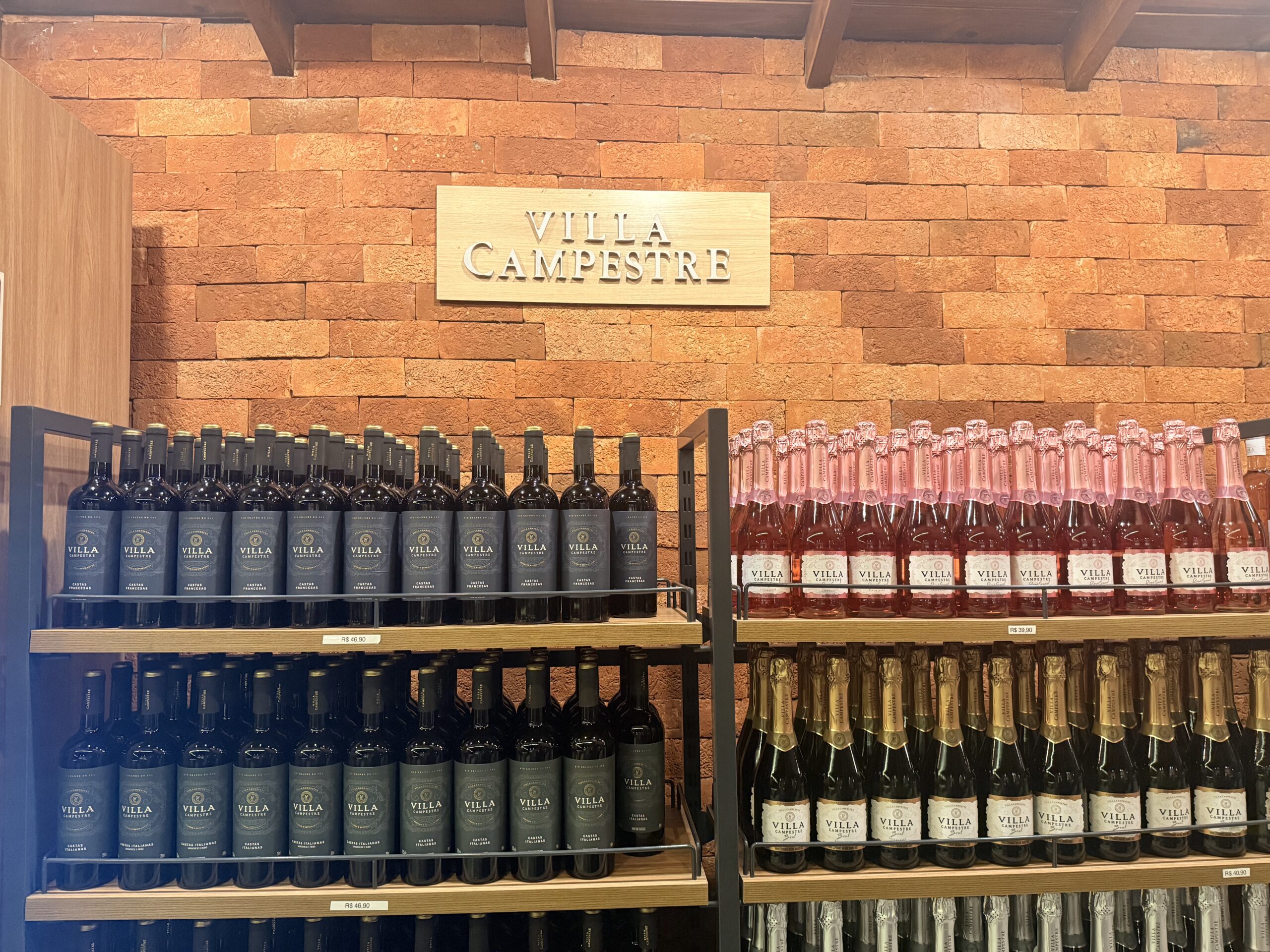 Placa Villa Campestre com vinhos expostos embaixo, em Pinheiros, São Paulo